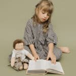 kind met boek en pop van poppentricot