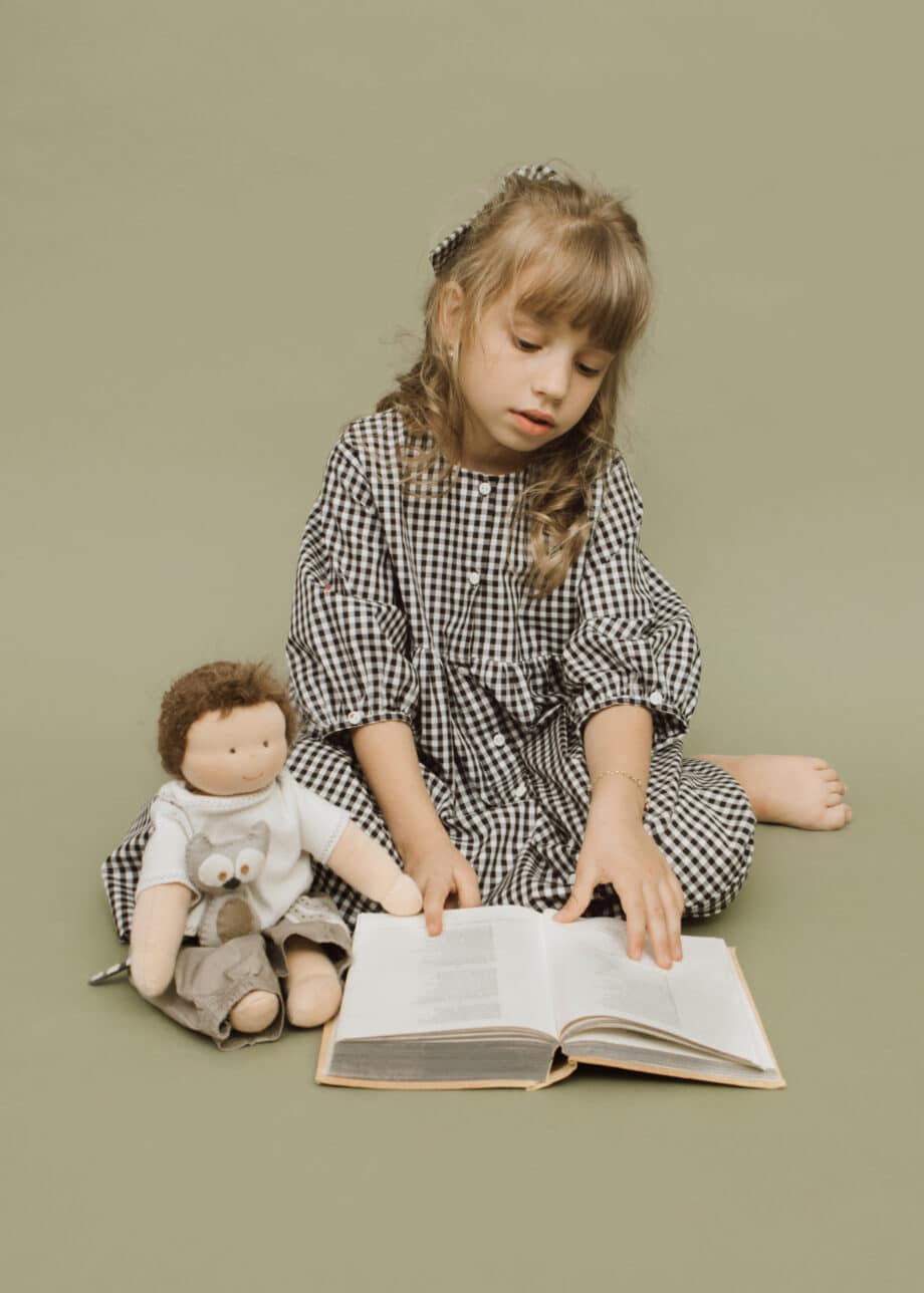 child with book and doll from poppentricot