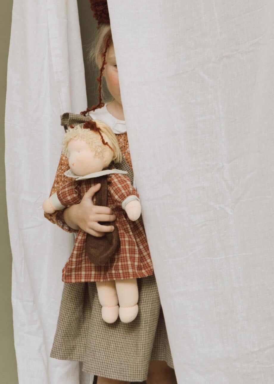 verstopt kind met pop in armen gemaakt van poppentricot