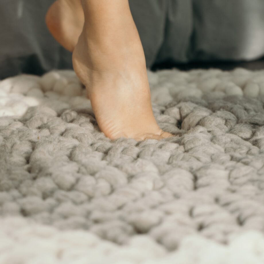 Voet op XXL gebreid vloerkleed van meervilt Europese Merino lontwol